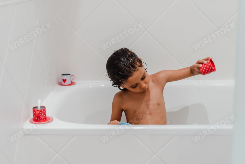 Little hispanic girl taking a shower playing with her toys
