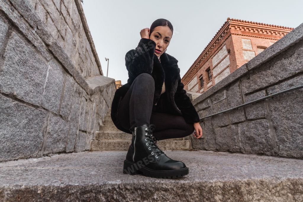 A hot stylish female wearing black clothes and posing on a stone staircase