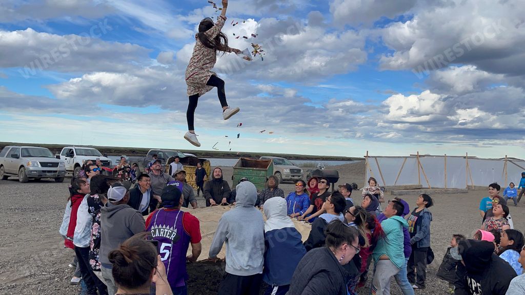 A group of people holding a trampoline for a person jumping on it