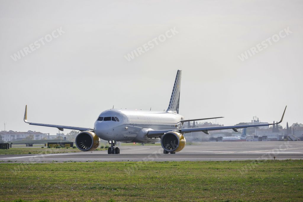 An Airbus A320-271N airplane of the Vueling airline, at Lisbon airport at sunrise, surrounded by a green lawn