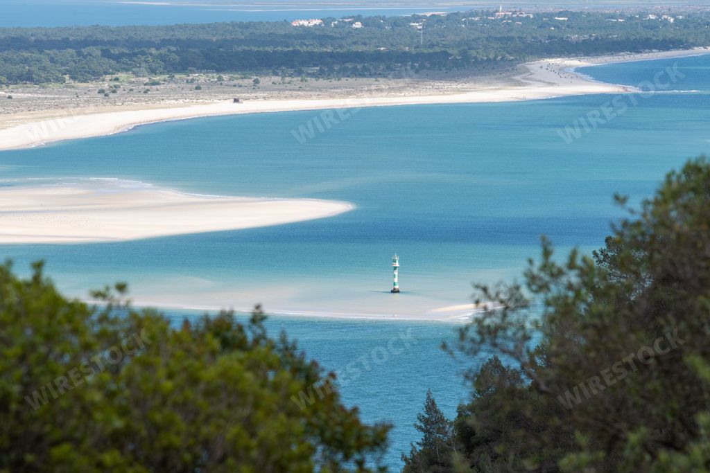 A beautiful landscape of the white Gale beach and a lighthouse in the ocean in Troia Peninsula, Portugal.