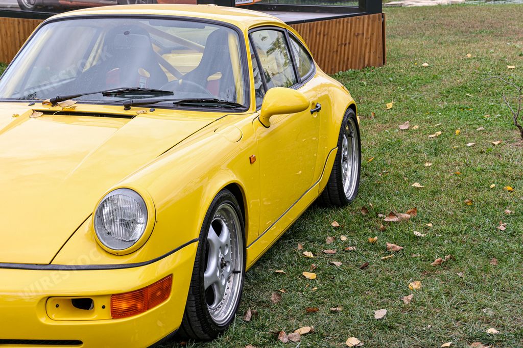 A yellow sports car Porsche standing on the green grass