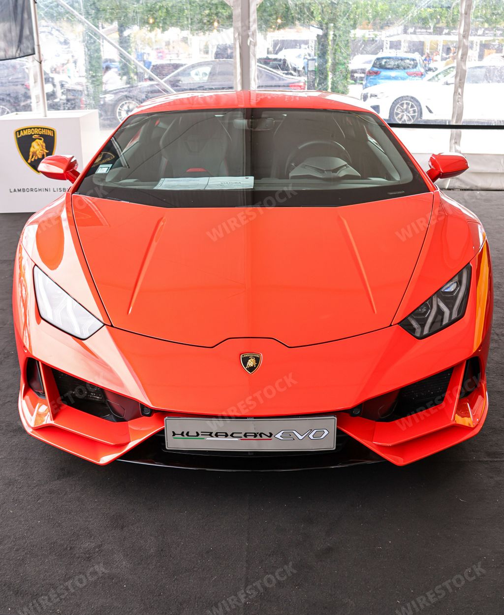 A vertical front view of a beautiful orange Lamborghini Huracan on a sunny day