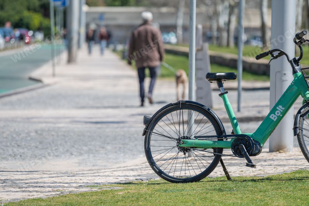 A beautiful shot of a green Bolt mobility bicycle on grassland available in the city of Lisbon, Portugal