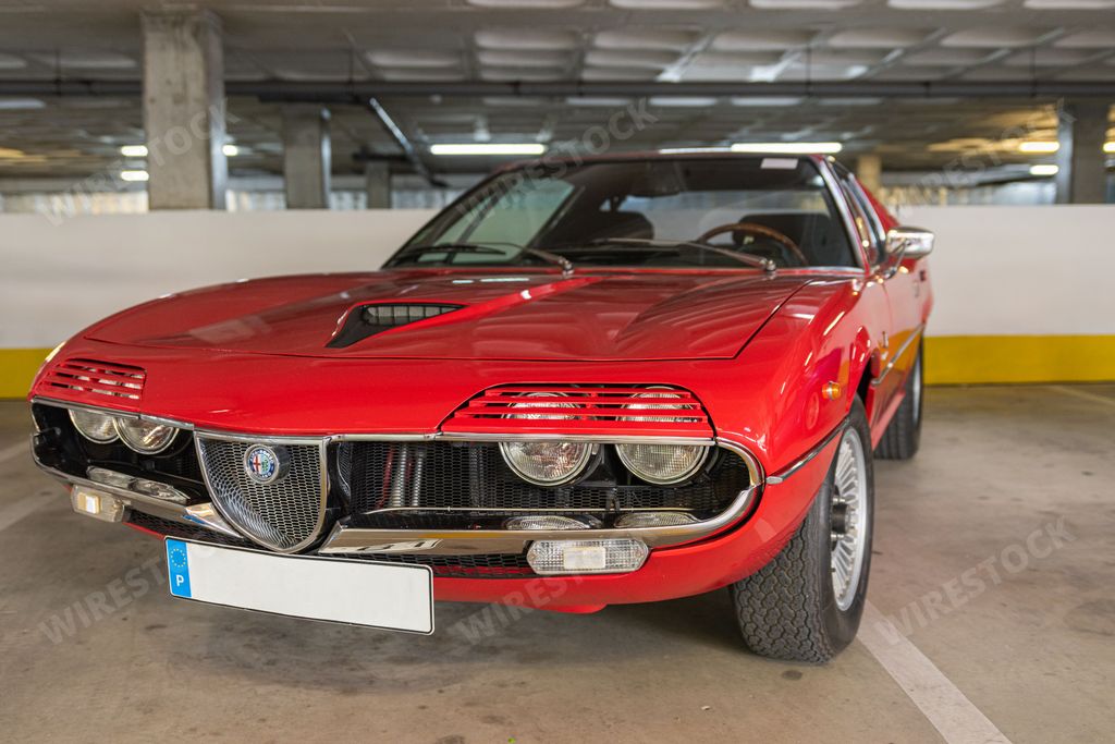 A closeup of the front view of a red vintage Coupe Alfa Romeo Montreal Coupe car in a garage