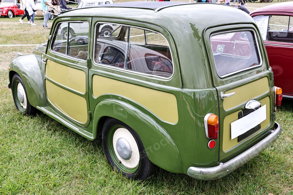 A side view of a beautiful classic green Fiat 500C Topolino in a field