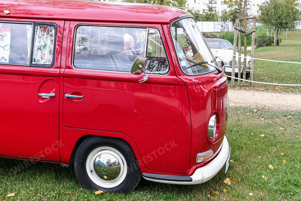 A beautiful bright red classic Volkswagen transporter van on a field