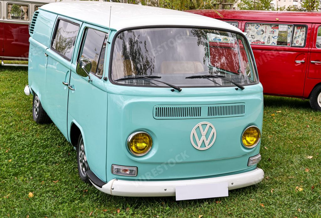 A beautiful bright turquoise classic Volkswagen transporter van on a field