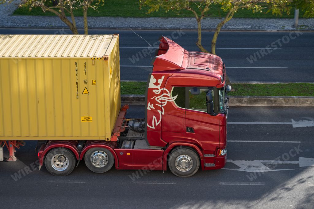 A red truck transporting cargo driving in the streets of Lisbon, Portugal