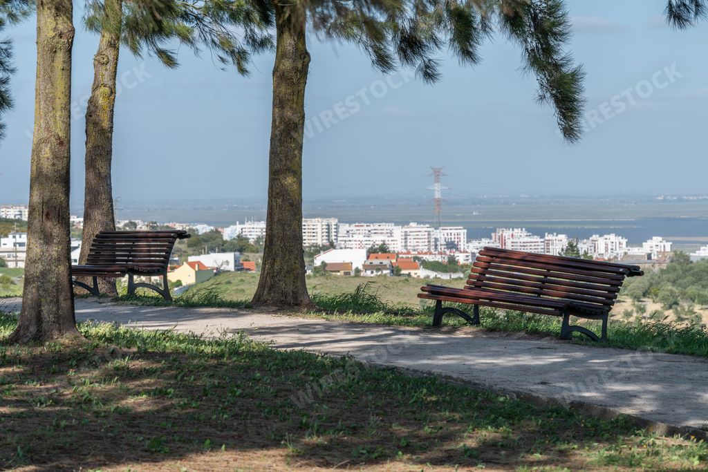 A path in the park with wooden benches on a background of the city of Loures, Portugal