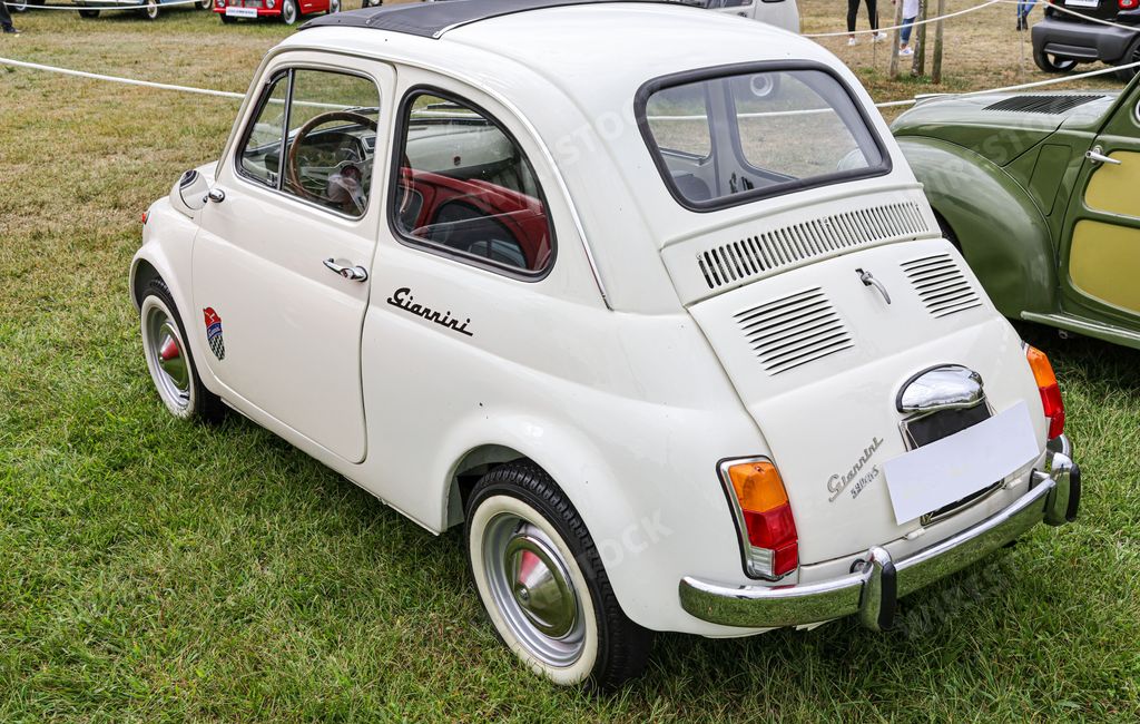 A rear view of a beautiful classic white Fiat Giannini 590 GTs in a field