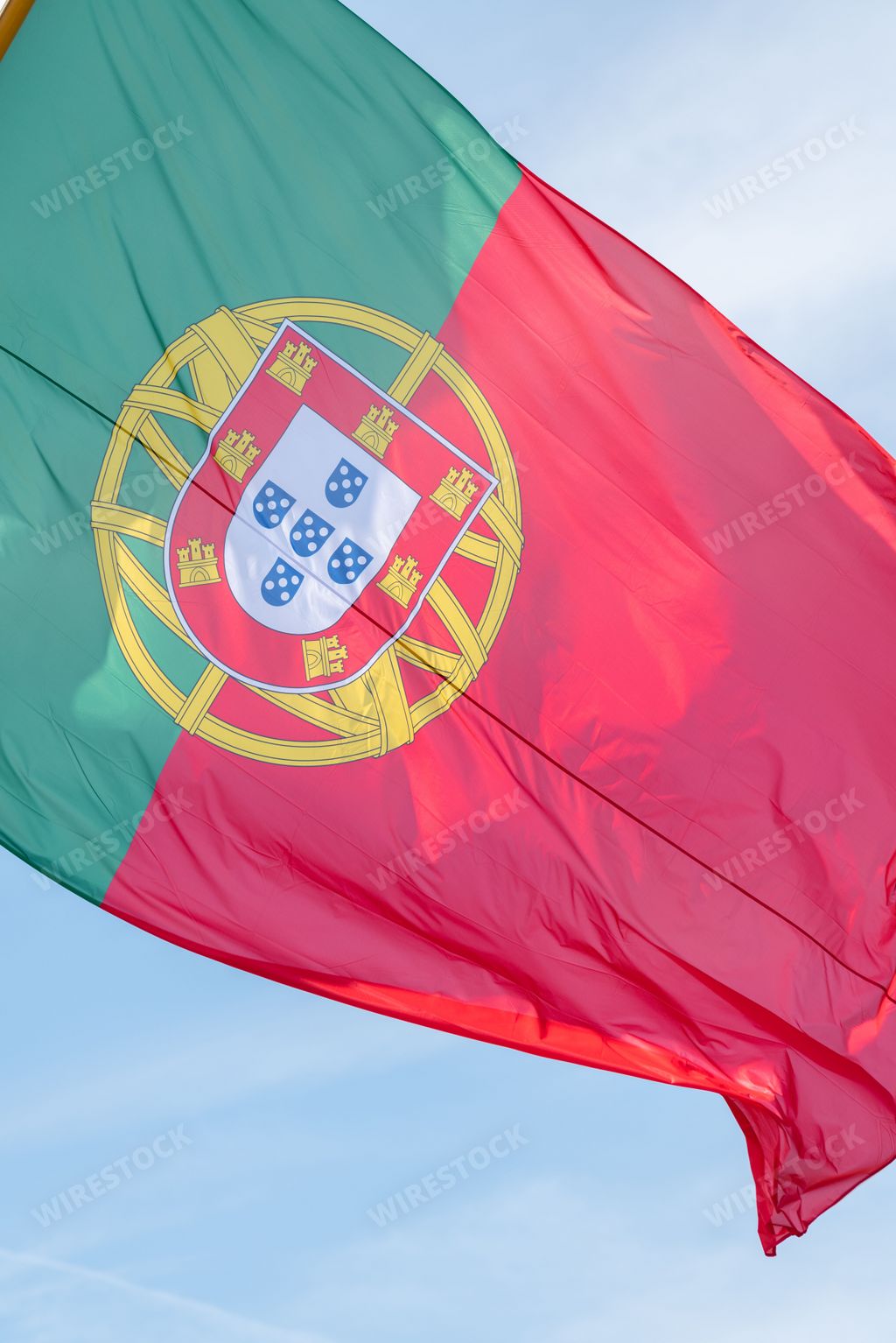 A vertical shot of Portugal flag waving during wind in background of sky