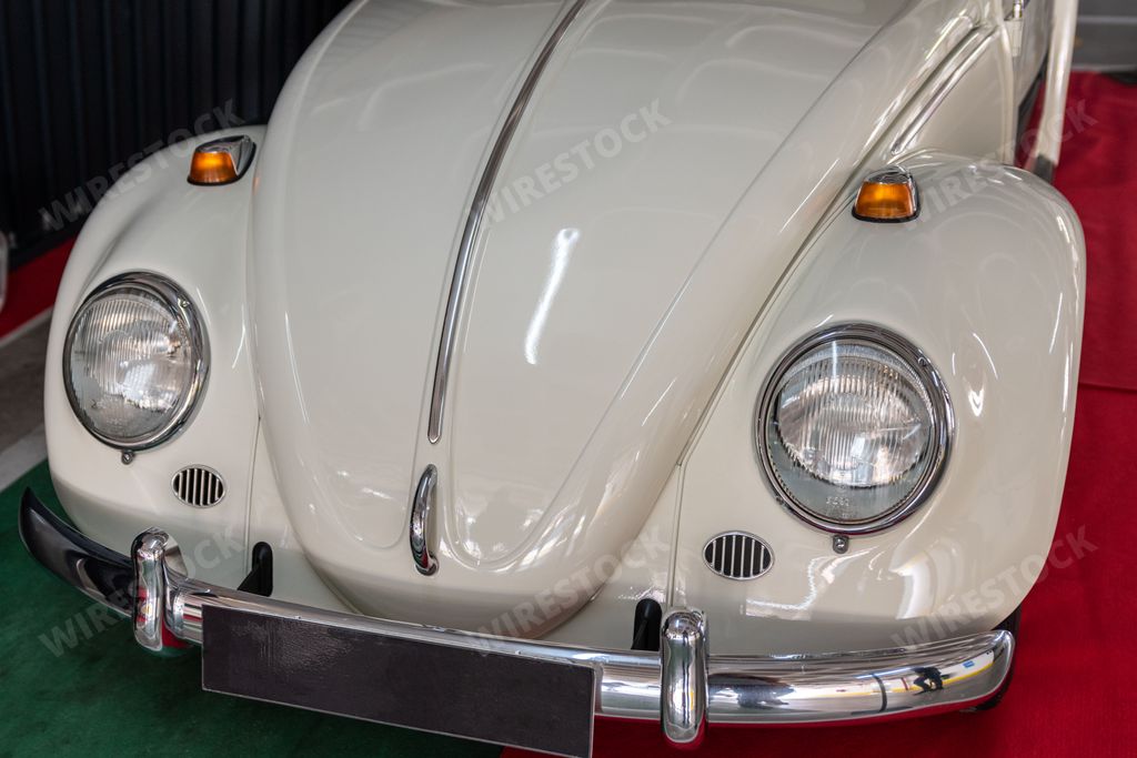 The frontal part of a vintage Volkswagen Beetle parked on red fabric.