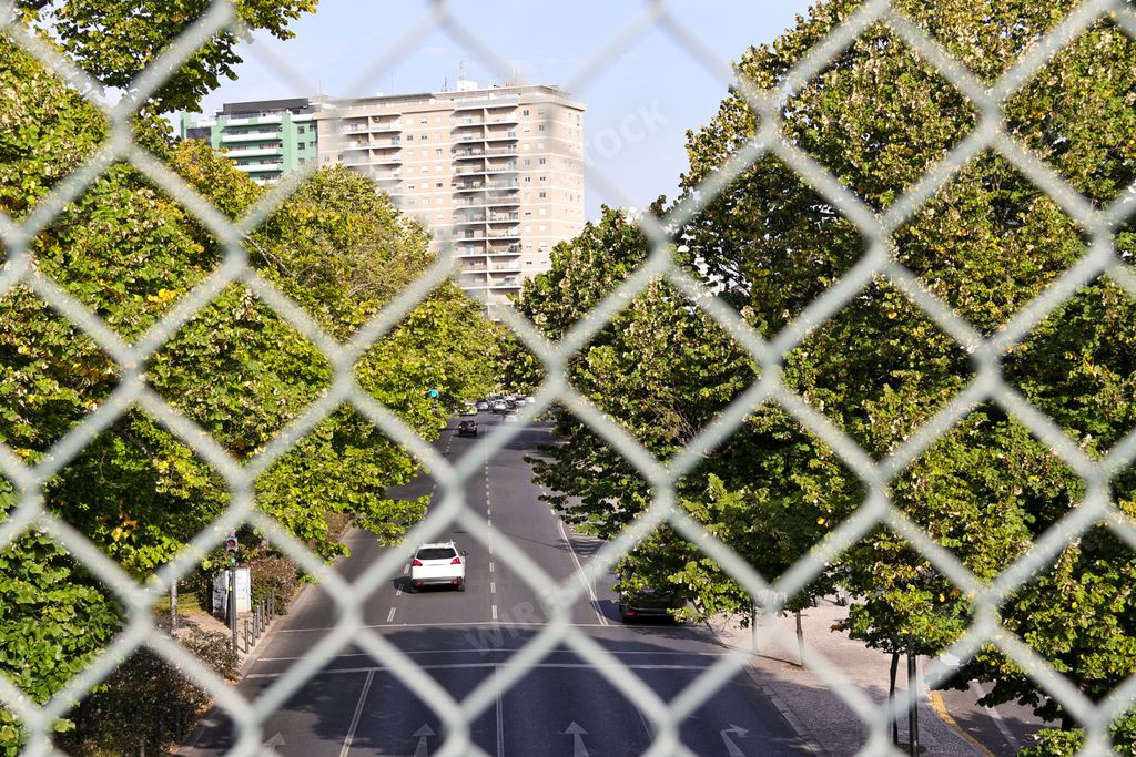 The view of the street along the Campo Grande Garden behind the mesh fences in Lisbon, Portugal