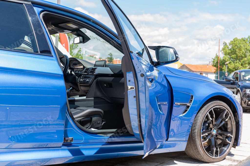 A closeup shot of a Blue BMW M4 Competition Coupe interior detail with opened door on a sunny day