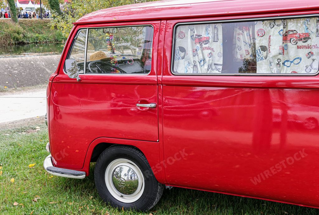 A beautiful bright red classic Volkswagen transporter van on a field