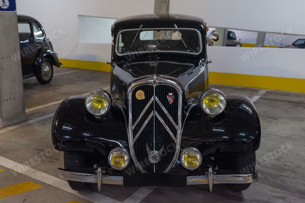 A closeup of the front view of a black vintage Citroen model Traction Avant car in a garage