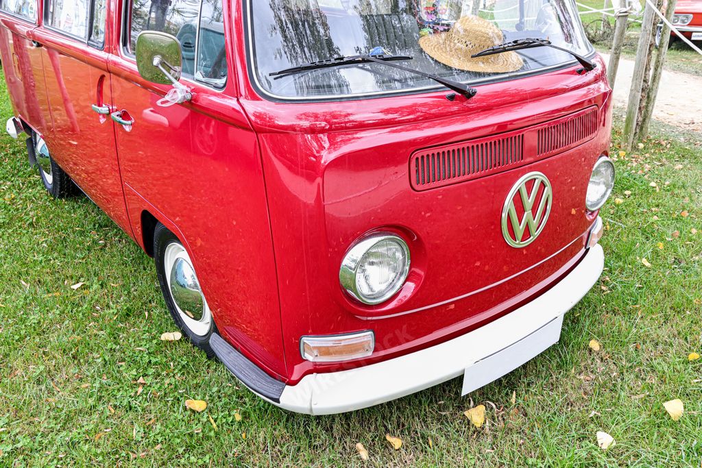 A beautiful bright red classic Volkswagen transporter van on a field