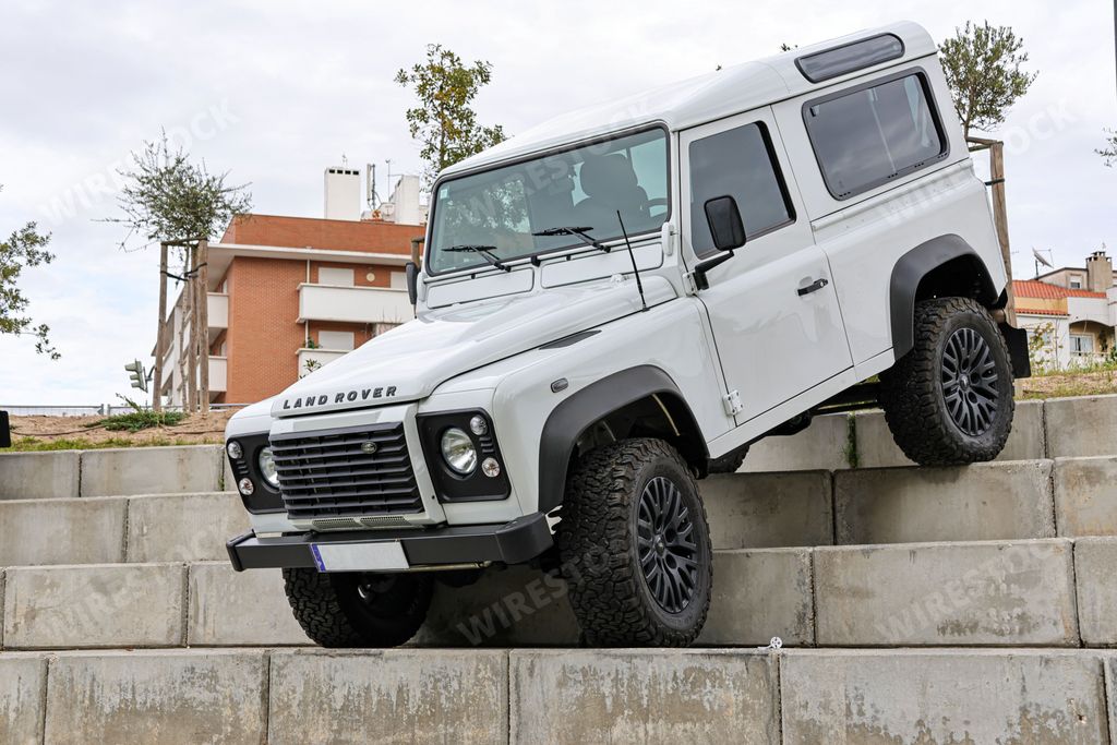 A white Land Rover Defender off-road jeep on concrete stairways during an exhibition in a park