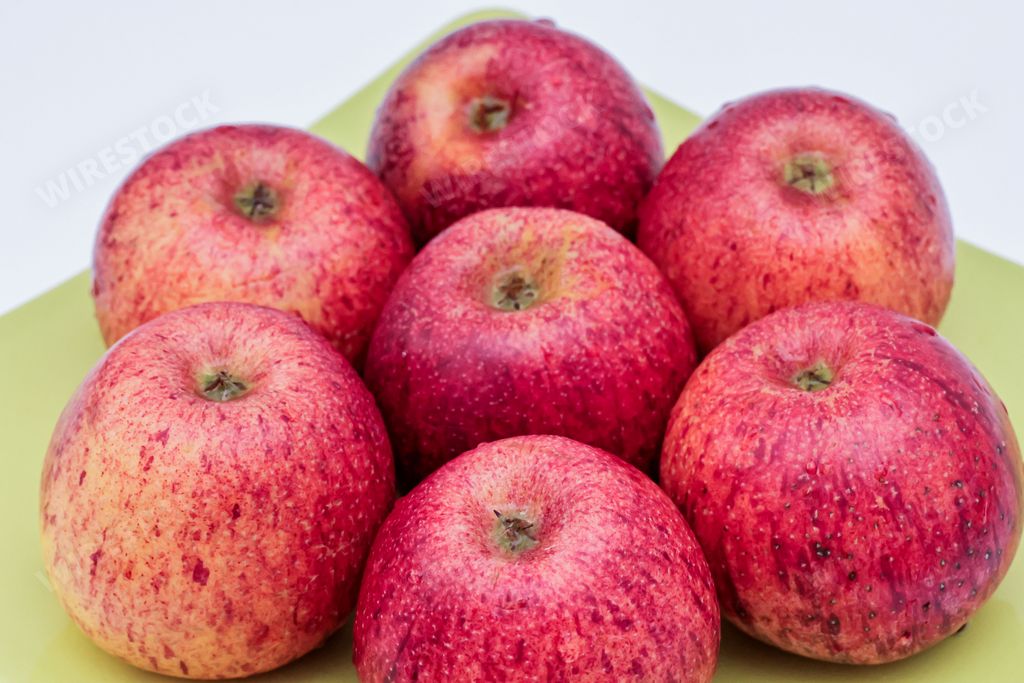 A top view of red apples of pero bravo esmolfe species washed with fresh water on a green plate