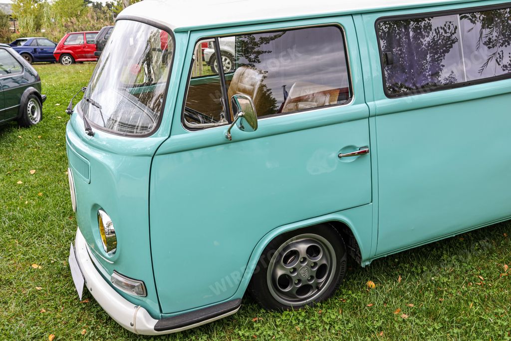 A beautiful bright turquoise classic Volkswagen transporter van on a field