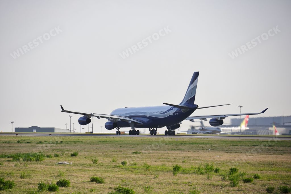 An Airbus A340-312 airplane of the airline company Hi Fly, at Lisbon airport at sunrise, surrounded by a green lawn