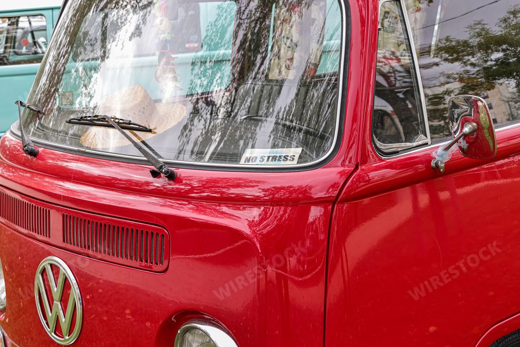 A beautiful bright red classic Volkswagen transporter van on a field