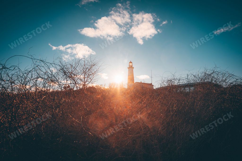 A silhouette of a lighthouse from the shore on the sunset