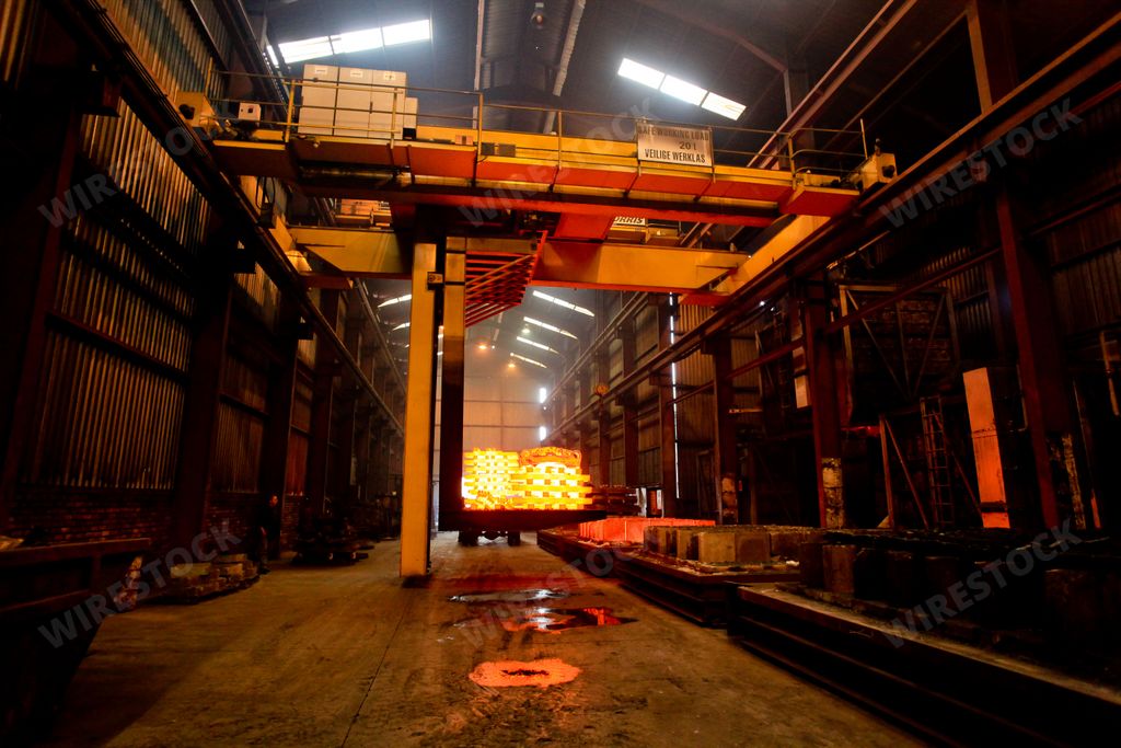 A low angle shot of hot molten forged steel rods outside a furnace inside a factory