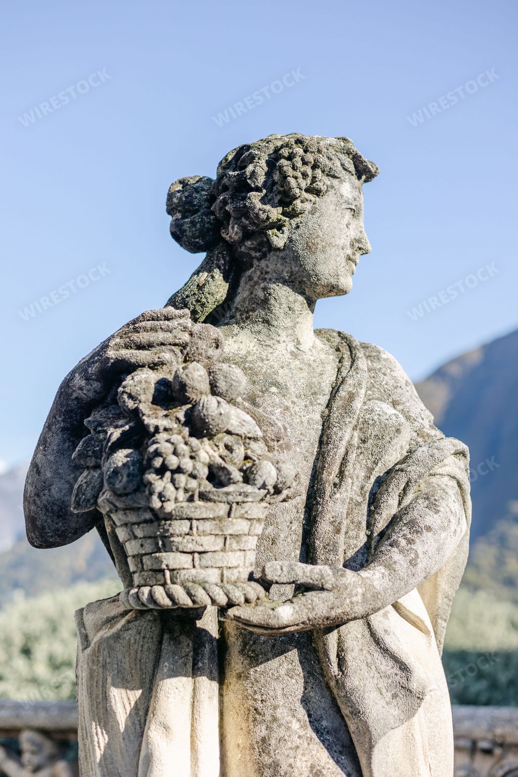 A closeup of female statue holding basket with fruits in park of Villa Balbianello