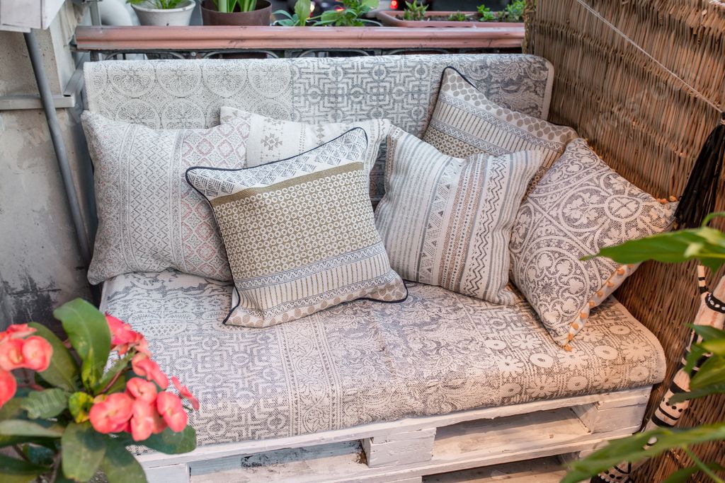 A comfy couch with pillows surrounded by houseplants