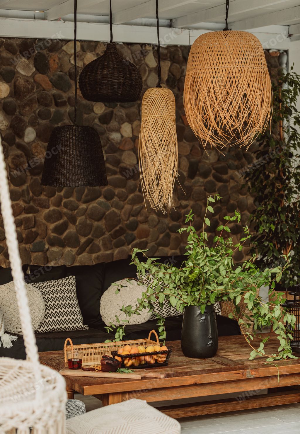 A vertical shot of decorative straw lamps over a wooden table in a veranda