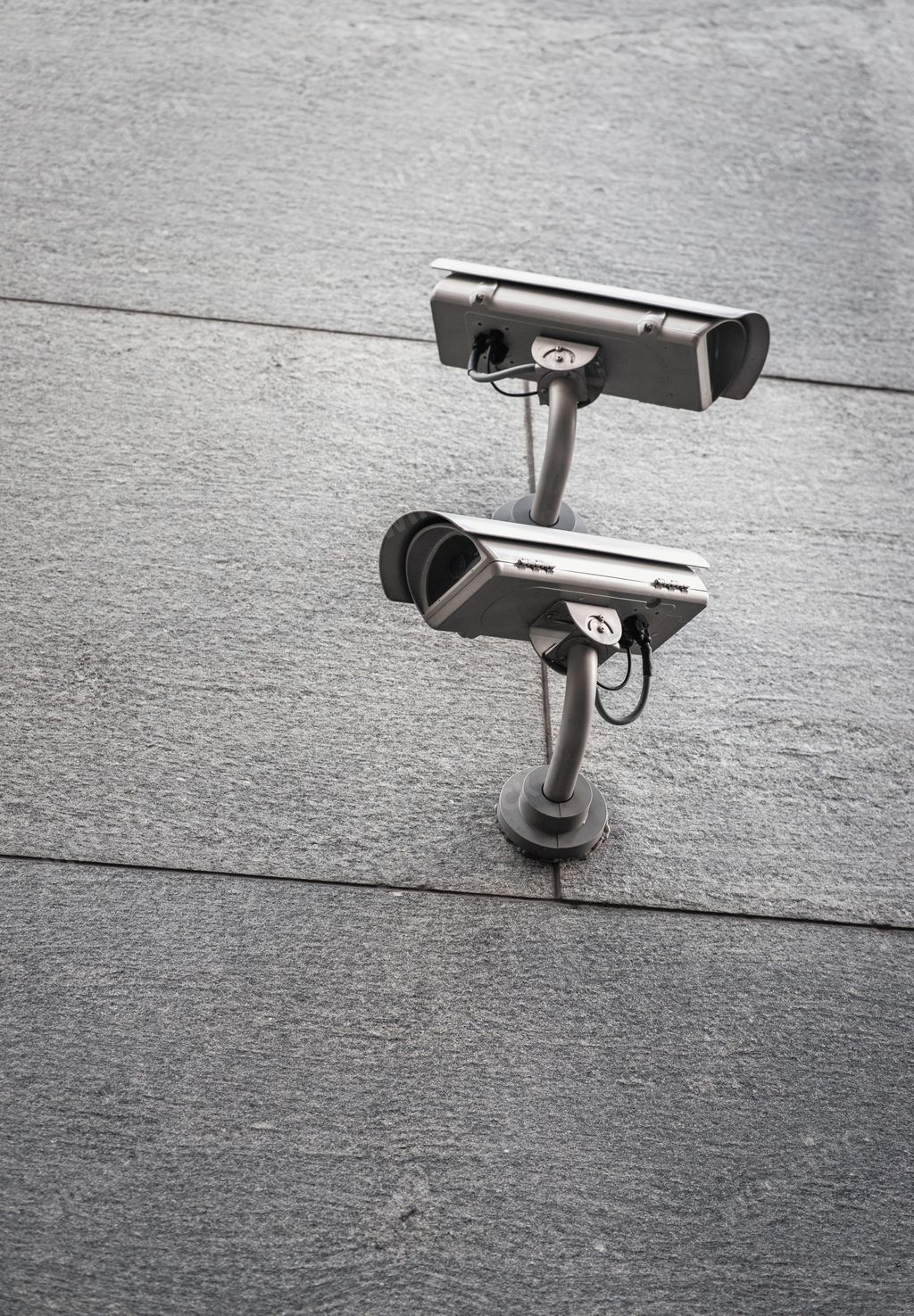A vertical shot of two street cameras facing opposite directions on a wall