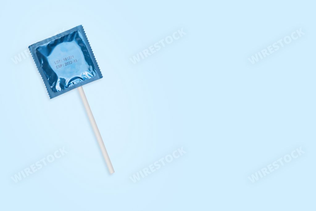 An overhead shot of a sealed lollipop condom on light blue background with space for your text