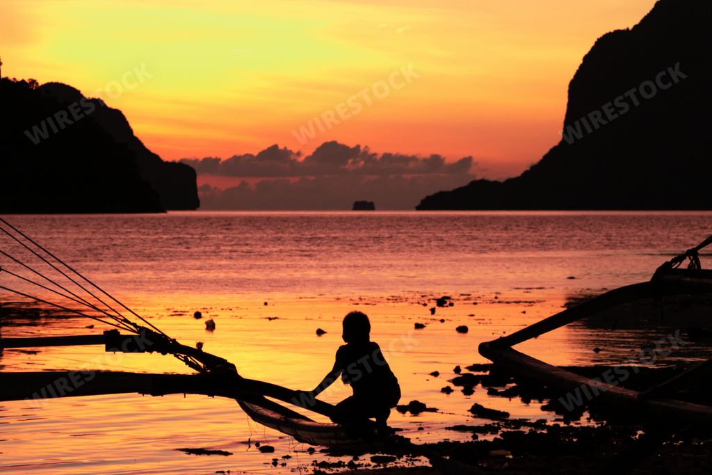 A silhouette of a kid on a beach in El Nido, Palawan island in the Philippines at sunset