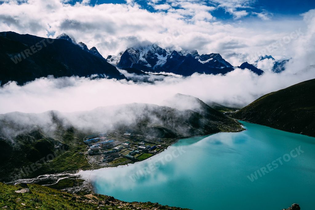 A beautiful shot of floating clouds over mountains near a blue lake