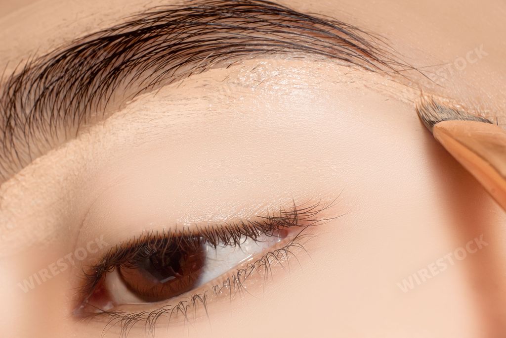 A close-up shot of a woman applying foundation cream with a brush.