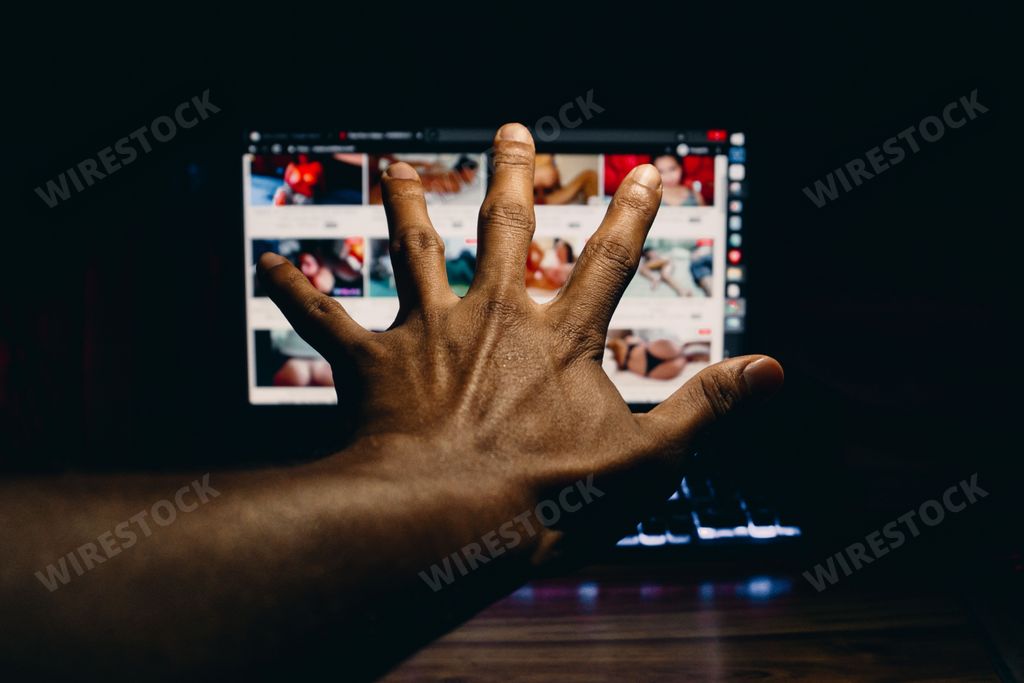 hands of a person covering the screen that contains pornographic images. drug concept.