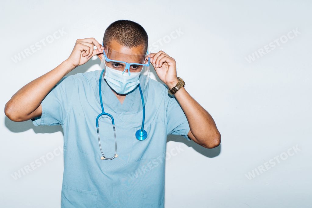 A portrait of male doctor putting on protective glasses - coronavirus, surgeons and pandemic concept