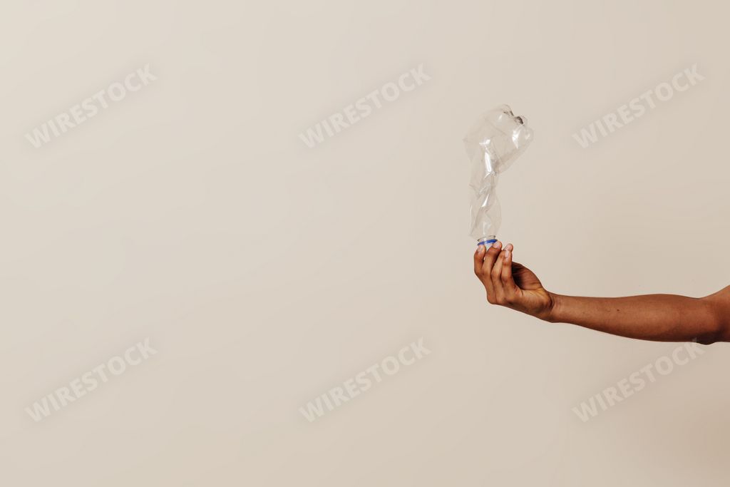 A closeup shot of a hand holding a plastic bottle- a recycling concept