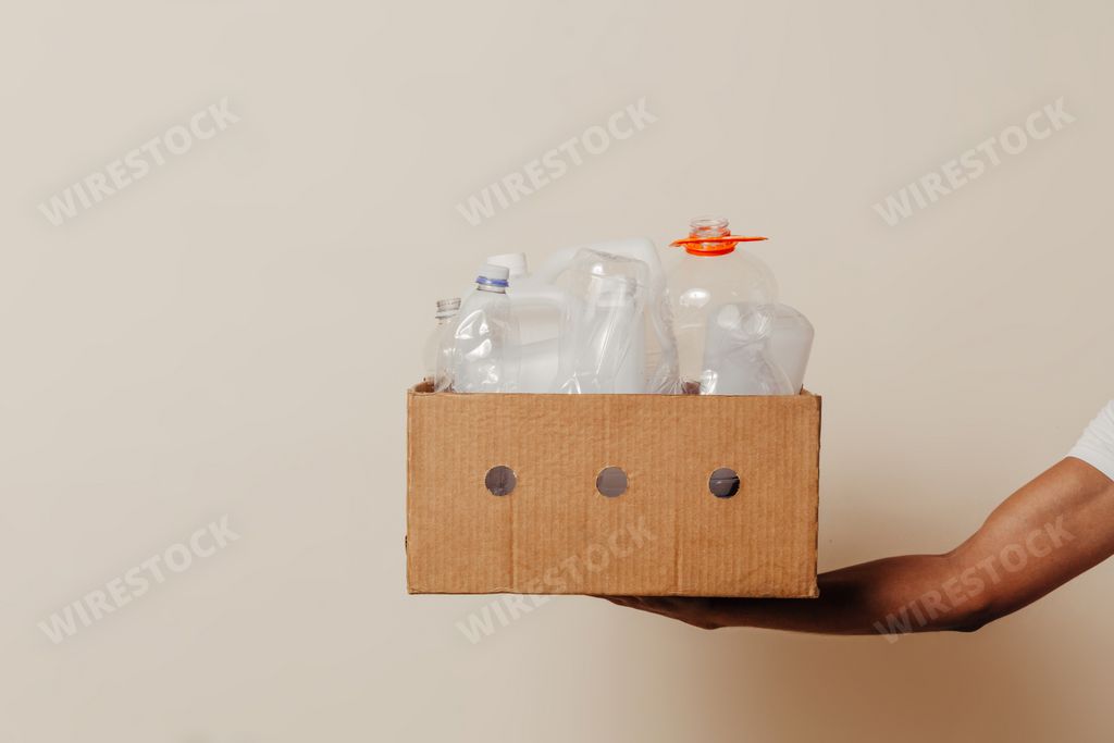 A closeup shot of a hand holding a box with plastic bottles - a recycling concept