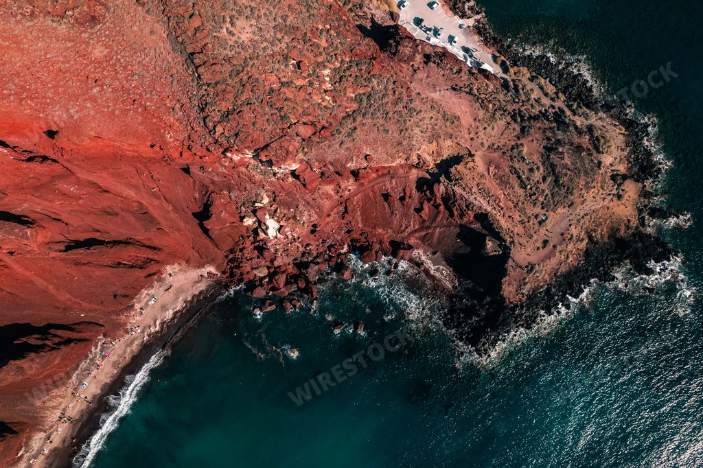 A breathtaking bird's eye view of the Red Beach in Santorini, Greece with a dark sea meeting the rocky cliffs