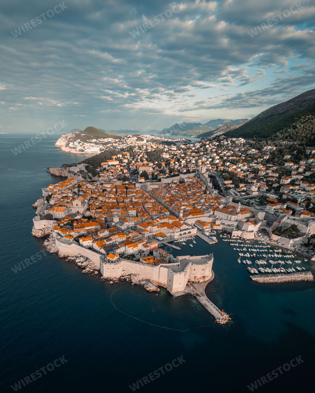 Aerial drone view of the Medival city of Dubrovnik at sunrise surrounded by large walls dropping into the Adriatic Sea.