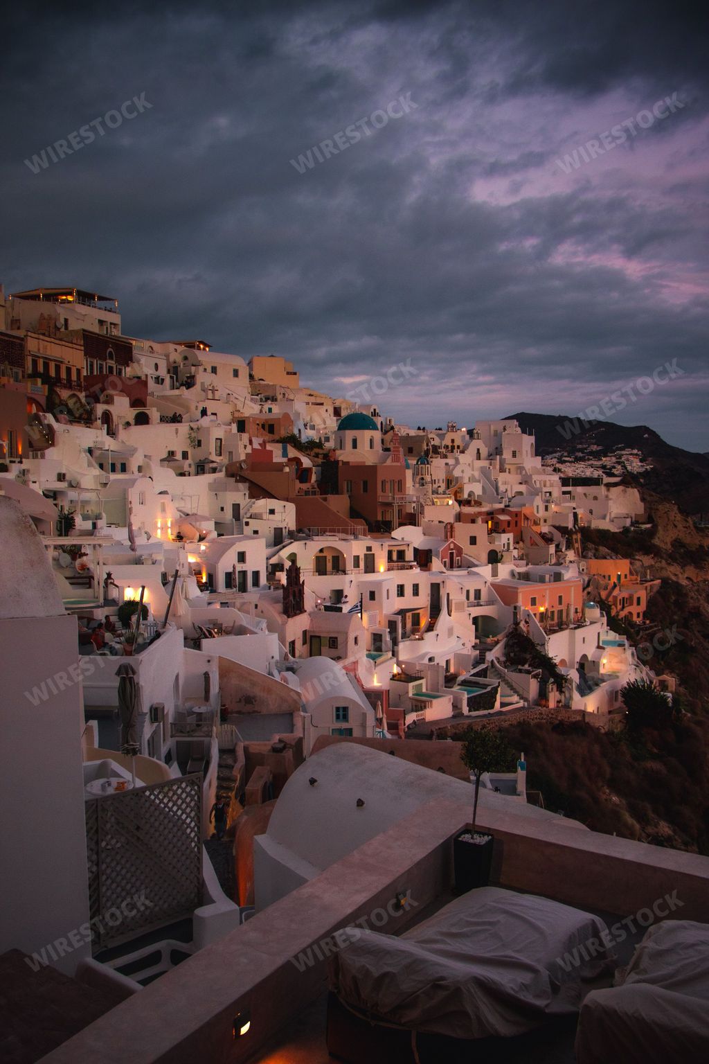 A gorgeous vertical shot of the village of Oia in Santorini, Greece with neat houses under a dark purple sky at sunset