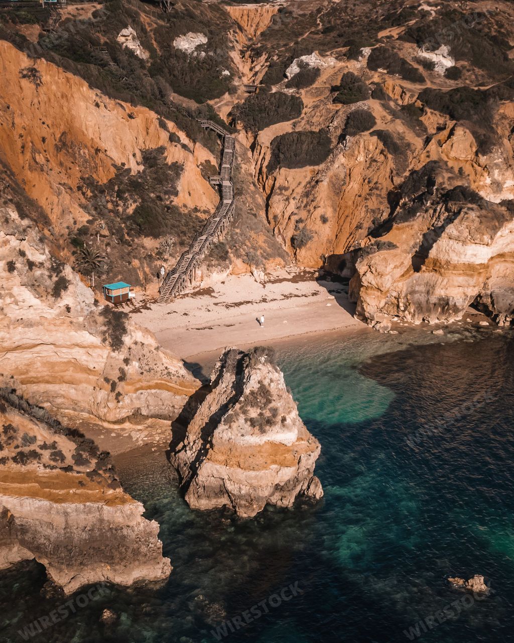 Sunrise at the beautiful cove of Praia do Camilo with a lone figure standing at the water's edge
