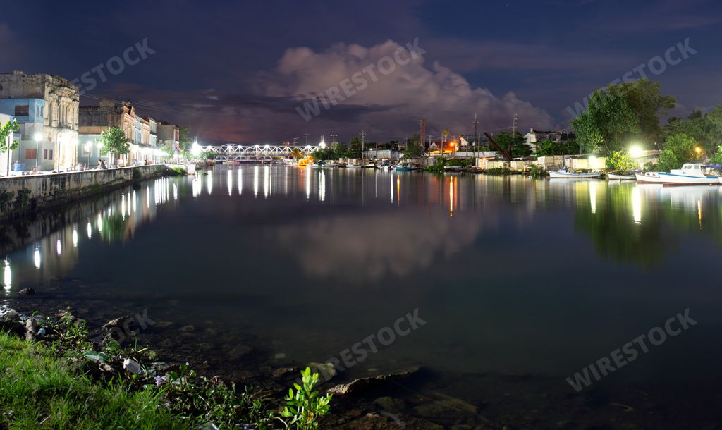 A beautiful view of an illuminated bridge over a calm river with light reflections at night