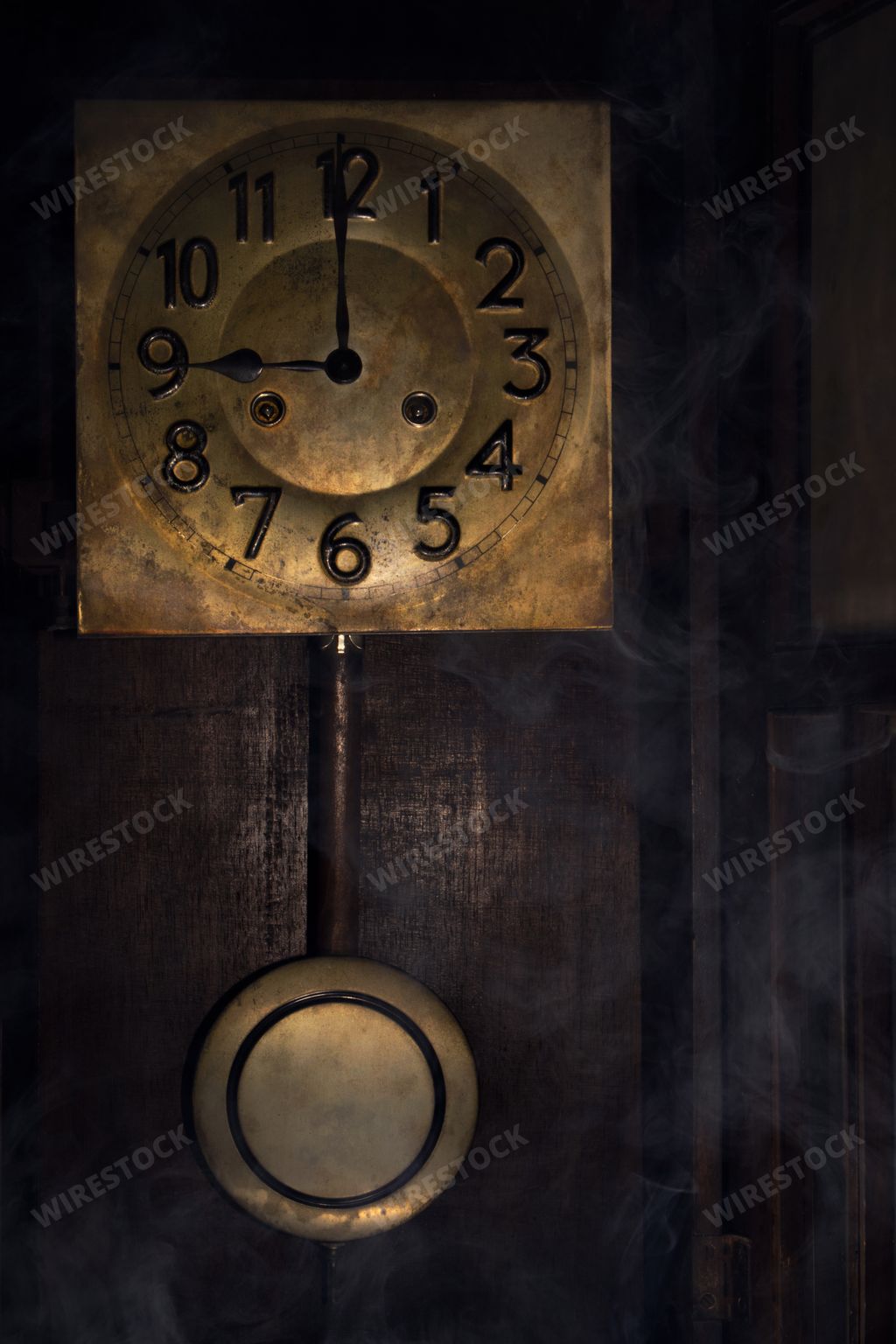 A closeup of a vintage clock hanging on a wall in a dark room