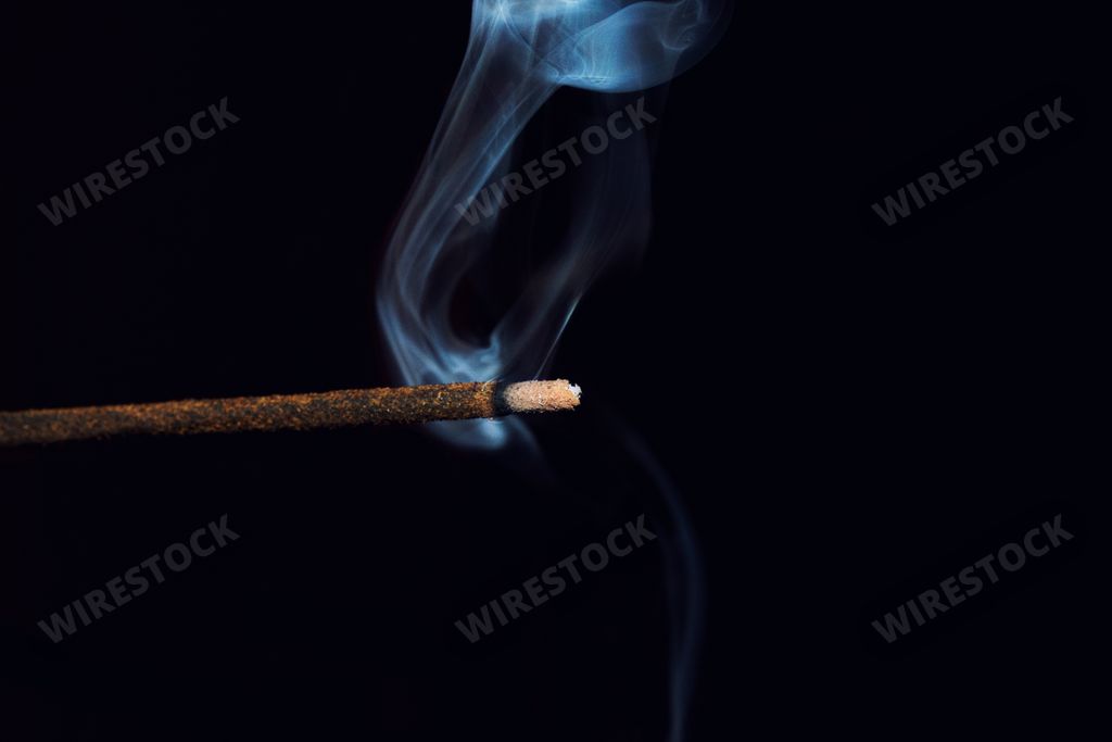 A smoking incense stick on a black background
