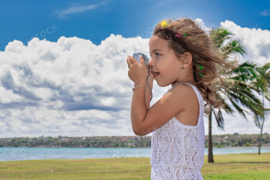 A beautiful Hispanic young girl taking photos on a beach
