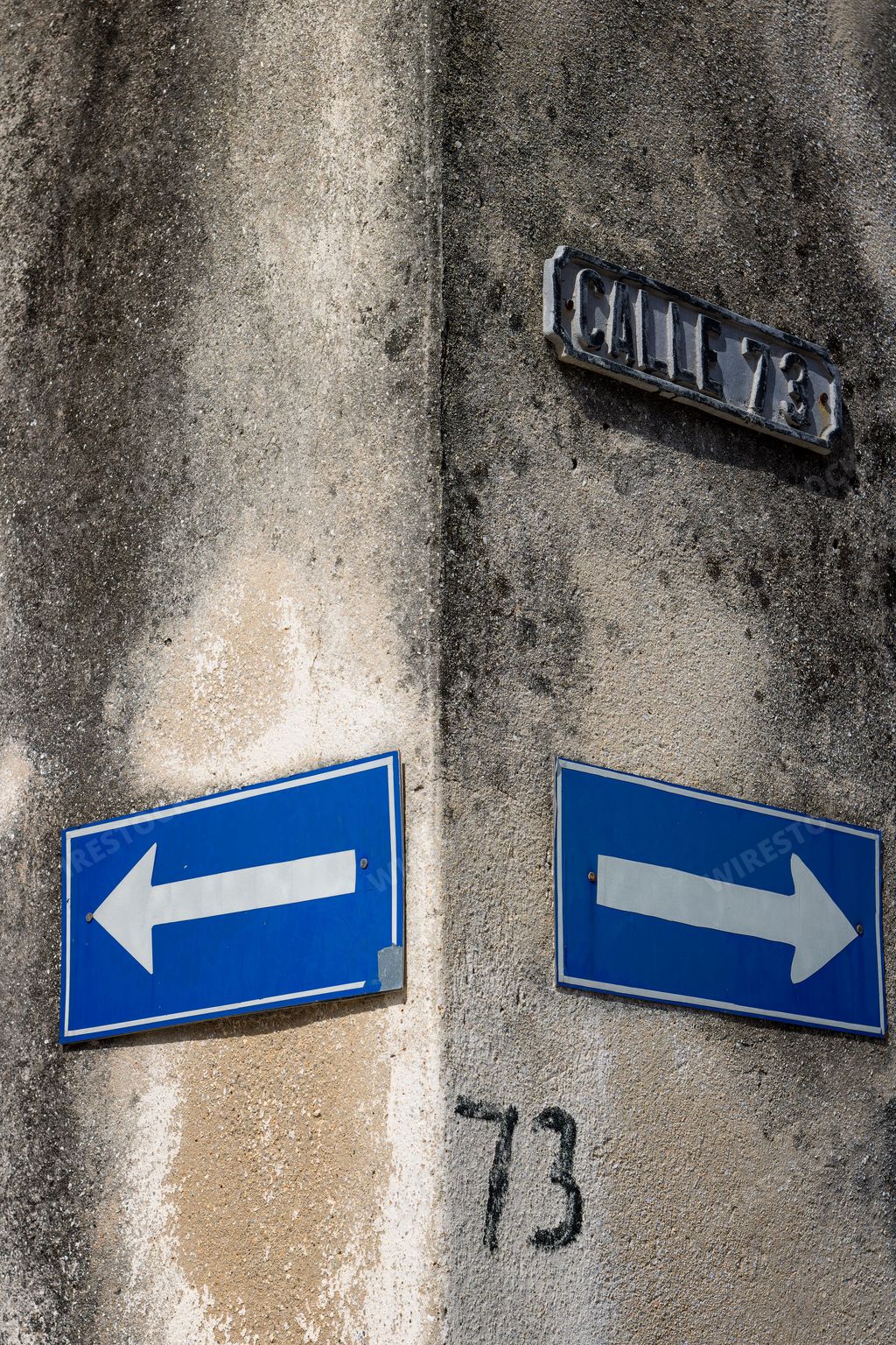 A vertical shot of road signs on a wall showing right and left on Cuban street